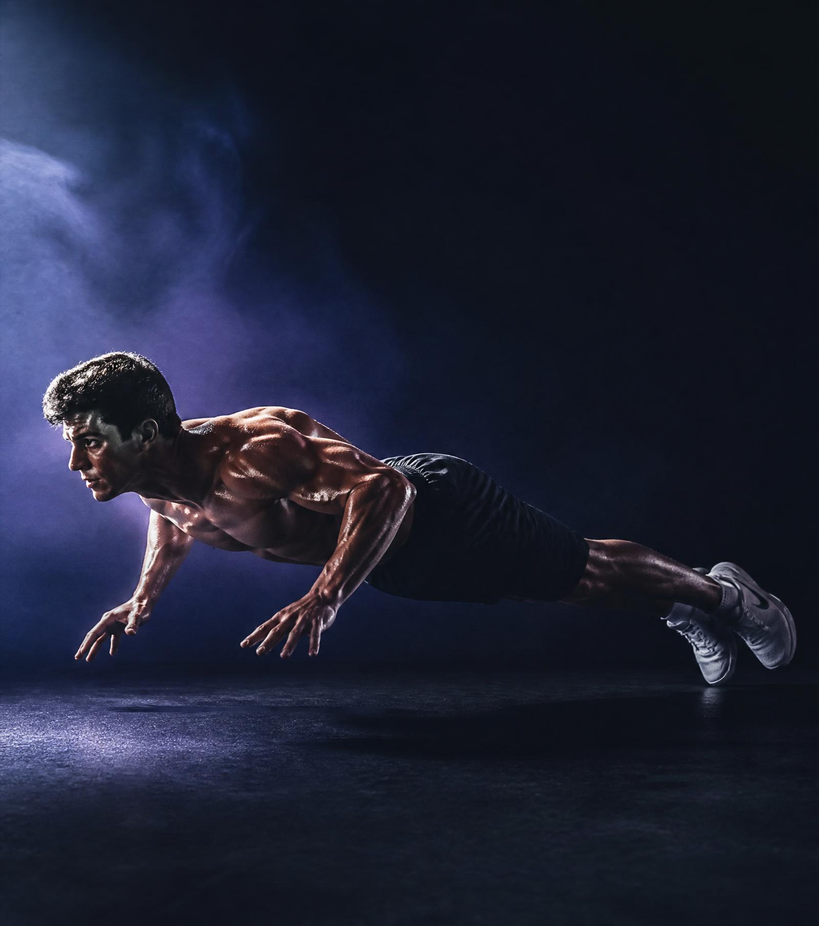 Athlete performing a controlled push-up in dramatic light